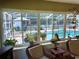 Bright sunroom with views of the pool area, adorned with hanging plants and cozy wicker seating at 3579 Sw Shorewood Dr, Dunnellon, FL 34431