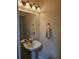 Cozy half bathroom featuring a pedestal sink, decorative mirror and lighting fixture at 3918 Sw 57Th Ave, Ocala, FL 34474