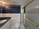 Bathroom featuring a shower/tub with gold trim, vanity, toilet and decorative blue wallpaper at 606 Midway Dr # B, Ocala, FL 34472
