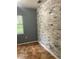Bedroom featuring eye-catching brick accent wall, neutral tile flooring, and bright window view at 6498 Se 167Th Ct, Ocklawaha, FL 32179