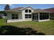 Exterior backyard view of home featuring a well-maintained lawn, back patio, and bright sunroom at 6836 Sw 112Th St, Ocala, FL 34476