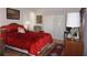 Inviting bedroom featuring a red comforter, side tables with lamps, and hardwood floors at 6836 Sw 112Th St, Ocala, FL 34476