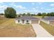 Charming single-story home with a well-manicured lawn, a two-car garage, and a paved driveway at 69 Juniper Trail Loop, Ocala, FL 34480