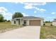 Single-story home with two-car garage, long driveway, and partially grassy yard at 69 Juniper Trail Loop, Ocala, FL 34480