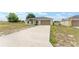 Single-story home with two-car garage, long driveway, and partially grassy yard at 69 Juniper Trail Loop, Ocala, FL 34480