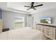 Bright bedroom features a large window, ceiling fan, and dresser, offering a comfortable and airy space at 9 Walnut Run, Ocala, FL 34480