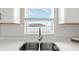 Close-up of a kitchen sink with stainless steel faucet, white countertops, and modern backsplash at 9 Walnut Run, Ocala, FL 34480