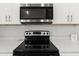 Close-up of the kitchen stove with a modern backsplash, quartz countertops, and white cabinets at 9 Walnut Run, Ocala, FL 34480