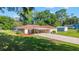 Well-maintained single-story home with long driveway, carport, lush lawn, and mature trees, offering great curb appeal at 10140 Sw 81St Terrace Rd, Ocala, FL 34481