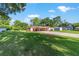 Spacious front yard with a well-maintained lawn and a house featuring a carport and long driveway on a sunny day at 10140 Sw 81St Terrace Rd, Ocala, FL 34481