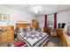 Spacious bedroom features a ceiling fan, a window with red curtains and warm wood laminate flooring at 10140 Sw 81St Terrace Rd, Ocala, FL 34481