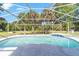Screened in pool with a covered lanai is surrounded by lush landscaping offering privacy at 10140 Sw 81St Terrace Rd, Ocala, FL 34481