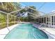 Beautiful screened in pool with a diving board is surrounded by a green lawn and tropical foliage at 10140 Sw 81St Terrace Rd, Ocala, FL 34481