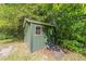 Exterior view of a green shed surrounded by trees, featuring a ramp and a small window at 10140 Sw 81St Terrace Rd, Ocala, FL 34481