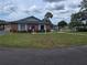 View of a brick building with blue trim, lawn and an access-controlled gate leading to an outdoor pool area at 10330 Sw 99Th Ave, Ocala, FL 34481