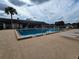Community pool surrounded by lounge chairs and tables, with trees and a building visible in the background at 10330 Sw 99Th Ave, Ocala, FL 34481