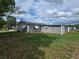Back of house with satellite dish, awnings, gray exterior, and a well-maintained green lawn at 10330 Sw 99Th Ave, Ocala, FL 34481