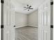View of a bedroom with grey wood flooring and a ceiling fan through a doorway at 1317 Ravida Woods Dr, Apopka, FL 32703