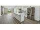 Modern kitchen with stainless steel refrigerator, gas range, and a large white island that opens into the living area at 1317 Ravida Woods Dr, Apopka, FL 32703