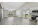 Bright living room with vaulted ceiling, large windows, and gray vinyl flooring and with partial view of the kitchen at 1317 Ravida Woods Dr, Apopka, FL 32703