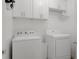 Bright laundry room featuring a white washer and dryer with matching cabinets and hanging rod for added convenience at 13618 Sw 111Th Cir, Dunnellon, FL 34432