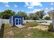 Spacious backyard featuring a blue storage shed, concrete patio with grill, and well-maintained lawn at 14118 Sw 32Nd Terrace Rd, Ocala, FL 34473