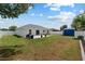 Well-maintained backyard with a concrete patio, a blue shed, lawn, and a white fence, ideal for outdoor activities at 14118 Sw 32Nd Terrace Rd, Ocala, FL 34473