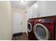 A modern laundry room has wooden floors, washer and dryer, a white back door, and overhead cabinets at 14118 Sw 32Nd Terrace Rd, Ocala, FL 34473