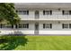 Exterior view of the condominium showcasing the white exterior, black shutters, balcony, well-kept lawn, and manicured shrubs at 1640 Ne 40Th Ave # 107, Ocala, FL 34470