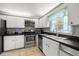 Charming kitchen features white cabinets, stainless appliances, tile flooring, and a window with patterned curtains at 1640 Ne 40Th Ave # 107, Ocala, FL 34470