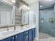 Modern bathroom features dual sinks, quartz countertop, blue cabinets, and glass shower at 16954 Se 93Rd Cuthbert Cir, The Villages, FL 32162