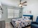 Cozy bedroom with a floral-patterned bedspread, ceiling fan, and neutral color scheme at 16954 Se 93Rd Cuthbert Cir, The Villages, FL 32162