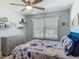 Well-lit bedroom with a floral-patterned bedspread, ceiling fan, and floating shelves at 16954 Se 93Rd Cuthbert Cir, The Villages, FL 32162