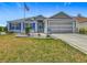 Charming single story home with manicured lawn and landscaping, an American flag, and a two-car garage at 16954 Se 93Rd Cuthbert Cir, The Villages, FL 32162