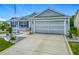 Charming home featuring blue shutters, a two-car garage, and a well-manicured yard with American flag at 16954 Se 93Rd Cuthbert Cir, The Villages, FL 32162