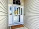 Close-up of the home's bright front door featuring a welcome mat and sunflower decoration at 16954 Se 93Rd Cuthbert Cir, The Villages, FL 32162