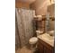 An earth-toned bathroom showcasing a shower with patterned curtain, toilet, sink, and open storage at 2151 Se 177Th Ave, Silver Springs, FL 34488