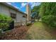 A well-kept backyard with a tall chimney, lush greenery, and an AC unit at 2272 Se Laurel Run Dr, Ocala, FL 34471