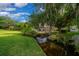 Lush backyard with mature trees, a charming stream, and a screened-in lanai at 2272 Se Laurel Run Dr, Ocala, FL 34471