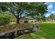 A picturesque backyard features a flowing stream, lush greenery, and a screened-in patio area at 2272 Se Laurel Run Dr, Ocala, FL 34471