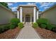 Home's entrance showing walkway leading to the front door framed by elegant columns and manicured bushes at 2272 Se Laurel Run Dr, Ocala, FL 34471