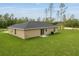 The backyard features a grassy lawn and a beige one story home with sliding glass doors at 23131 Sw Rainelle Rd, Dunnellon, FL 34431