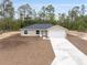Exterior shot of single-story home showcasing a long driveway and manicured front yard at 23131 Sw Rainelle Rd, Dunnellon, FL 34431