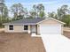 Exterior shot of single-story home showcasing manicured front yard and neutral color scheme at 23131 Sw Rainelle Rd, Dunnellon, FL 34431