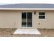Back exterior view of a beige single-story home with a sliding glass door and small concrete porch at 23131 Sw Rainelle Rd, Dunnellon, FL 34431
