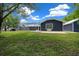 Lush backyard view featuring a screened-in pool, green lawn, and the back of a charming dark blue home at 260 Country Circle W Dr, Port Orange, FL 32128