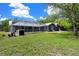 Expansive backyard featuring a screened-in pool, lush green lawn, and a well-maintained dark blue home exterior at 260 Country Circle W Dr, Port Orange, FL 32128