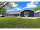 Well-kept backyard showcasing a screened-in pool, expansive lawn, and the rear of a stylish dark blue home at 260 Country Circle W Dr, Port Orange, FL 32128