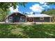 Charming single-story home featuring navy siding, metal roof, well-manicured lawn, and welcoming front entrance with vibrant orange door at 260 Country Circle W Dr, Port Orange, FL 32128