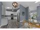 Modern kitchen with white cabinets, stainless steel appliances, stylish backsplash, a round glass-top dining table, and wood-look flooring at 260 Country Circle W Dr, Port Orange, FL 32128